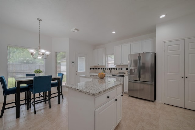 11943 Natural Bridges Ln, Sugar Land, TX 77498 - kitchen featuring stainless steel appliances, a center island, a chandelier, white cabinetry, and light stone counters