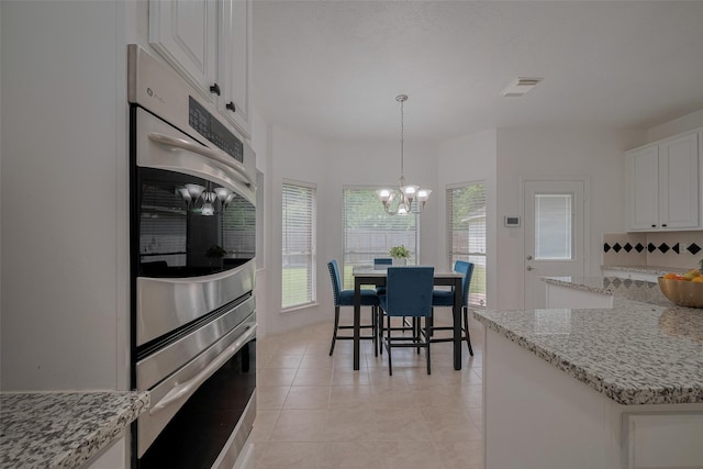 11943 Natural Bridges Ln, Sugar Land, TX 77498 - kitchen with a chandelier, white cabinetry, light stone counters, and light tile patterned flooring