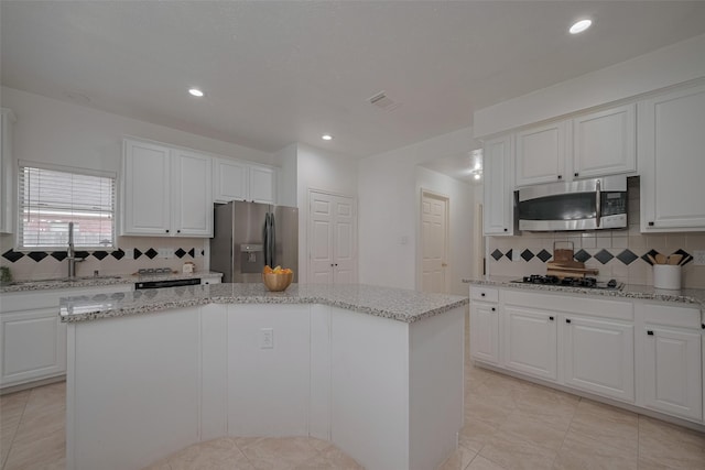 11943 Natural Bridges Ln, Sugar Land, TX 77498 - kitchen with stainless steel appliances, a sink, a center island, decorative backsplash, and white cabinets