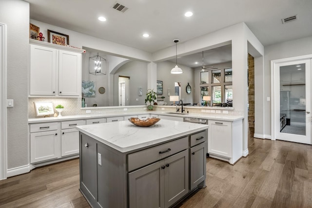 2715 Merlin Way, Katy, TX 77493 - kitchen with a sink, a kitchen island, wood finished floors, arched walkways, and hanging light fixtures