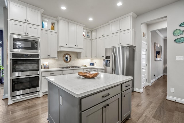2715 Merlin Way, Katy, TX 77493 - kitchen with appliances with stainless steel finishes, gray cabinetry, a kitchen island, white cabinetry, and wood finished floors