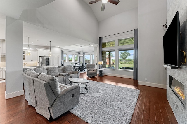 2603 Open Prairie Ln, Katy, TX 77493 - living area with a glass covered fireplace, dark wood-style floors, a ceiling fan, baseboards, and high vaulted ceiling
