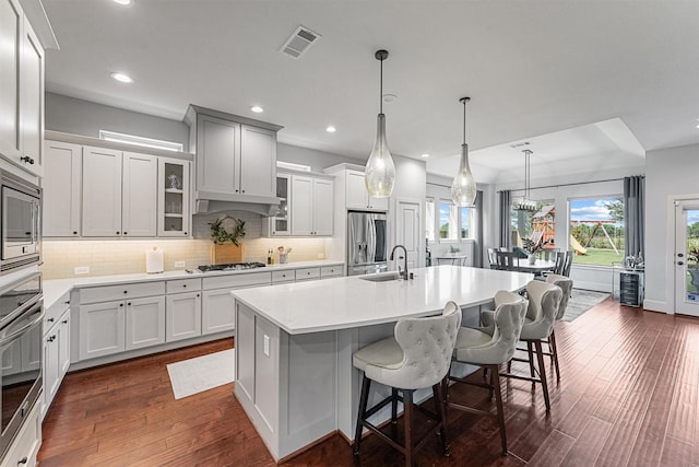 2603 Open Prairie Ln, Katy, TX 77493 - kitchen featuring stainless steel appliances, a sink, a kitchen breakfast bar, an island with sink, and dark wood finished floors