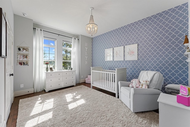 2603 Open Prairie Ln, Katy, TX 77493 - bedroom featuring wallpapered walls, a chandelier, baseboards, wood finished floors, and a nursery area