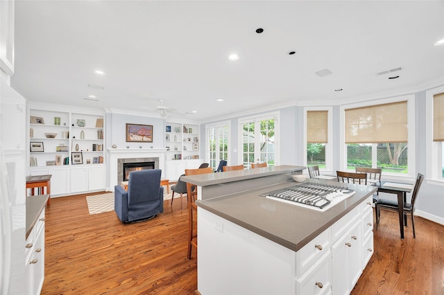 3509 Gramercy St, Houston, TX 77025 - kitchen with white gas cooktop, a ceiling fan, crown molding, light wood finished floors, and a tiled fireplace
