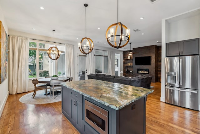 815 E 27th St, Houston, TX 77009 - kitchen featuring stainless steel appliances, a chandelier, light wood-style flooring, light stone counters, and recessed lighting