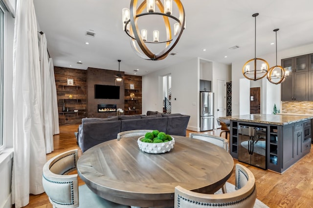 815 E 27th St, Houston, TX 77009 - dining space featuring a chandelier, beverage cooler, light wood-style flooring, recessed lighting, and wooden walls