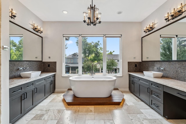 815 E 27th St, Houston, TX 77009 - full bathroom with two vanities, backsplash, a soaking tub, stone tile flooring, and recessed lighting