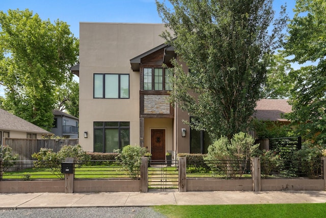 815 E 27th St, Houston, TX 77009 - modern home featuring stucco siding, a gate, a fenced front yard, and stone siding