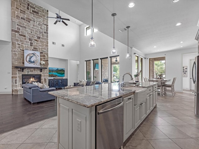 19003 Cove Manor Dr, Cypress, TX 77433 - kitchen featuring stainless steel dishwasher, a sink, ceiling fan, light tile patterned floors, and an island with sink