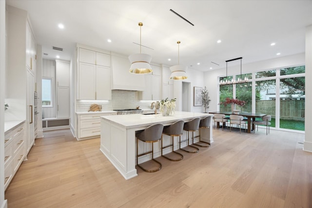 806 Holton St, Bellaire, TX 77401 - kitchen featuring a sink, light wood-style flooring, white cabinets, backsplash, and recessed lighting