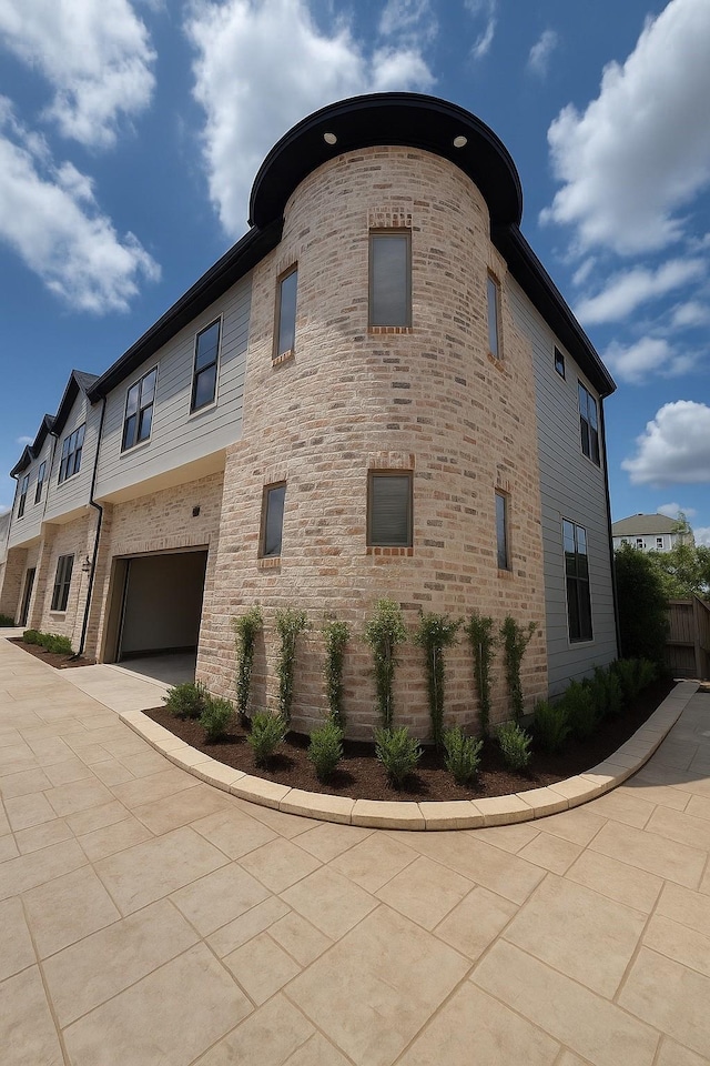 2594 W Tidwell Rd, Houston, TX 77091 - view of side of property with a garage, driveway, and stone siding