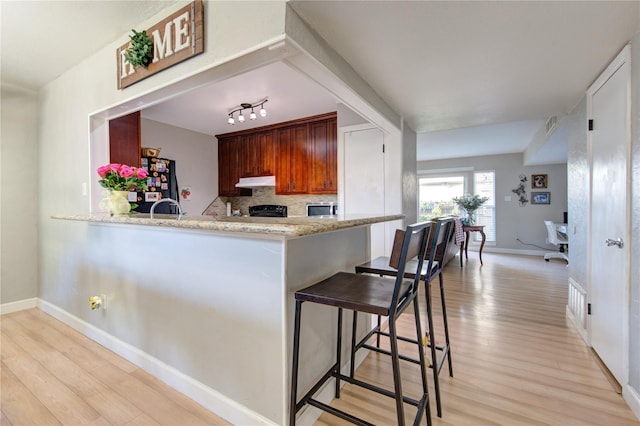 18218 Heritage Ln Unit 8218, Houston, TX 77058 - kitchen featuring freestanding refrigerator, light wood-style flooring, under cabinet range hood, and baseboards