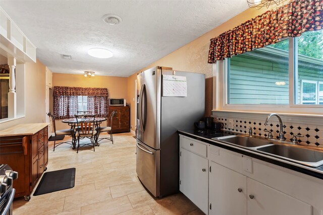 1518 14th Ave N, Texas City, TX 77590 - kitchen featuring a sink, stainless steel appliances, a textured ceiling, and white cabinetry