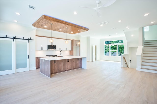 2117 Sauer St, Houston, TX 77004 - kitchen featuring stainless steel microwave, open floor plan, a kitchen island with sink, light countertops, and light wood-type flooring