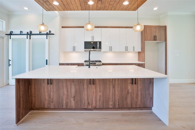 2117 Sauer St, Houston, TX 77004 - kitchen featuring stainless steel microwave, crown molding, white cabinetry, a large island, and a barn door