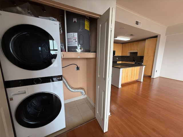 3505 Sage Rd Unit 1807, Houston, TX 77056 - laundry area featuring stacked washer / drying machine, wood finished floors, crown molding, and water heater
