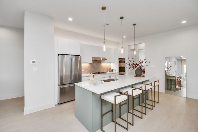 3002B Ventas Dr, Houston, TX 77047 - kitchen with stainless steel appliances, a sink, under cabinet range hood, white cabinets, and backsplash