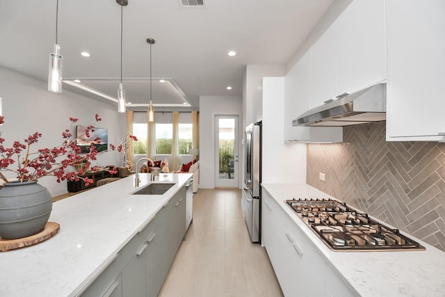 3002B Ventas Dr, Houston, TX 77047 - kitchen with under cabinet range hood, a sink, stainless steel appliances, tasteful backsplash, and pendant lighting