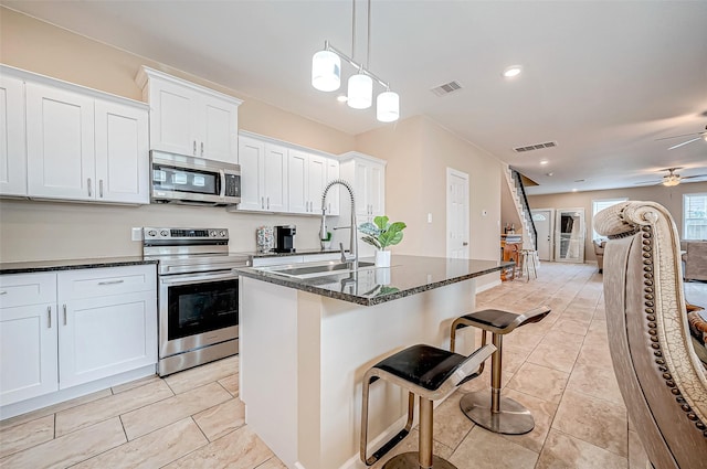 6702 Utah St, Houston, TX 77091 - kitchen with stainless steel appliances, a sink, dark stone countertops, a kitchen island with sink, and white cabinets