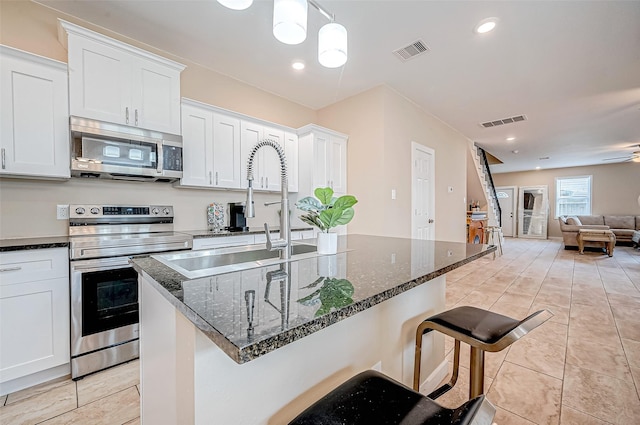 6702 Utah St, Houston, TX 77091 - kitchen with appliances with stainless steel finishes, open floor plan, white cabinetry, dark stone countertops, and a kitchen island with sink