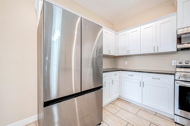 6702 Utah St, Houston, TX 77091 - kitchen with appliances with stainless steel finishes, dark countertops, white cabinetry, and light tile patterned flooring