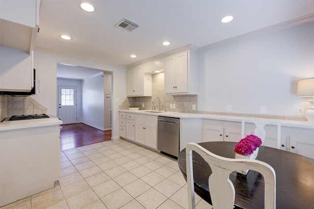 502 Enid St, Houston, TX 77009 - kitchen featuring appliances with stainless steel finishes, crown molding, light tile patterned flooring, white cabinets, and backsplash