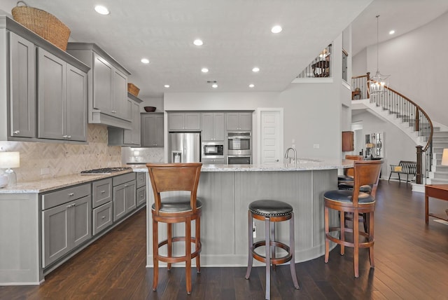 6602 Rochester Lake Loop, Katy, TX 77493 - kitchen with gray cabinetry, appliances with stainless steel finishes, dark wood-style floors, tasteful backsplash, and a kitchen breakfast bar