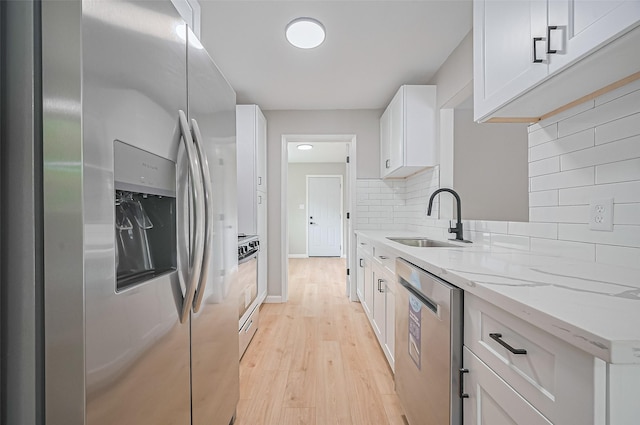 10623 Dunvegan Way, Houston, TX 77013 - kitchen featuring appliances with stainless steel finishes, a sink, light stone countertops, light wood-style flooring, and white cabinetry