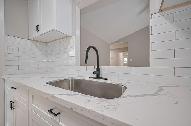 10623 Dunvegan Way, Houston, TX 77013 - kitchen with a sink, vaulted ceiling, decorative backsplash, light stone counters, and white cabinetry