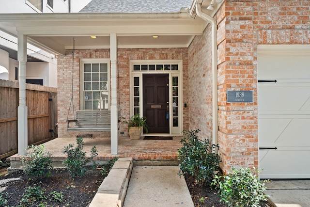 1938 Norfolk St, Houston, TX 77098 - doorway to property featuring covered porch, a shingled roof, and brick siding