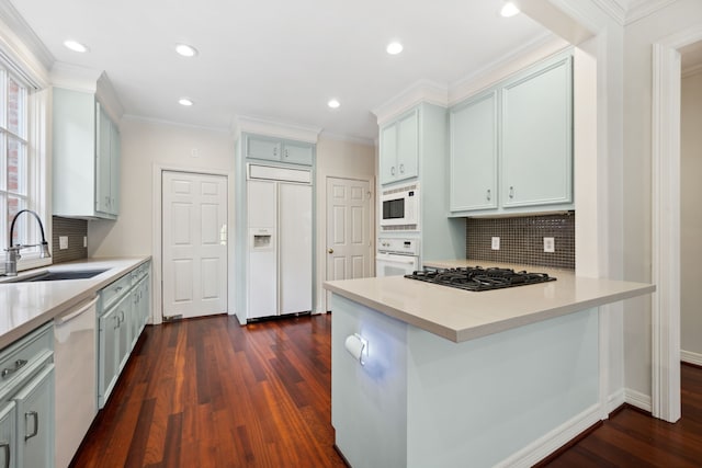 1938 Norfolk St, Houston, TX 77098 - kitchen with built in appliances, a sink, a peninsula, dark wood finished floors, and tasteful backsplash