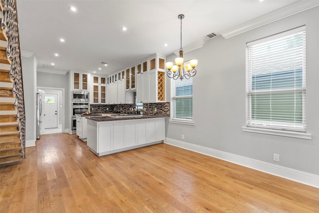 1509 Summer St, Houston, TX 77007 - kitchen featuring stainless steel appliances, ornamental molding, a chandelier, white cabinets, and tasteful backsplash