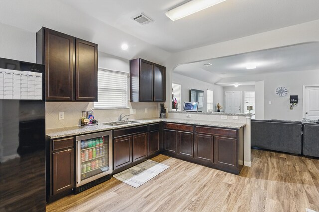 12911 Italian Cypress Trl, Houston, TX 77044 - kitchen featuring beverage cooler, a sink, a peninsula, open floor plan, and light wood finished floors