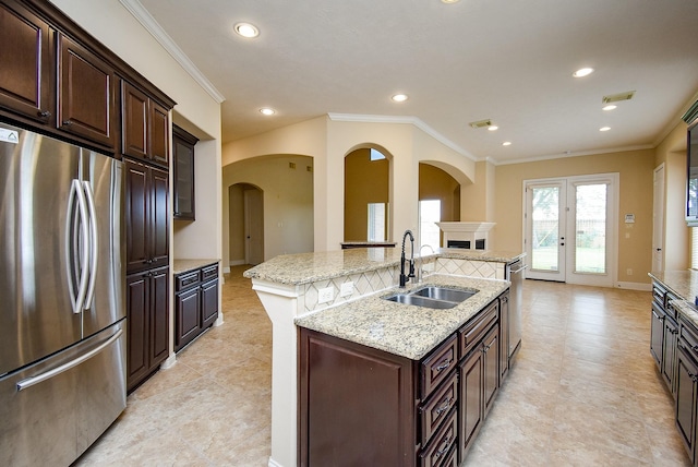1611 Whitfield St, Sugar Land, TX 77479 - kitchen featuring appliances with stainless steel finishes, a sink, arched walkways, a center island with sink, and crown molding