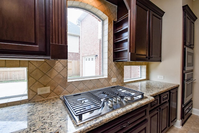 1611 Whitfield St, Sugar Land, TX 77479 - kitchen featuring appliances with stainless steel finishes, decorative backsplash, dark brown cabinetry, light stone countertops, and baseboards