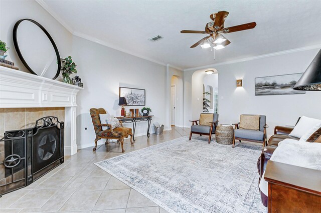 2102 Ivy Cove Ct, Katy, TX 77494 - living area with arched walkways, light tile patterned floors, ornamental molding, ceiling fan, and a tiled fireplace