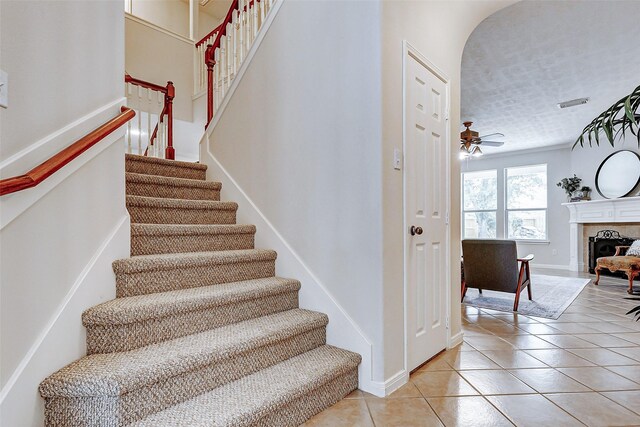 2102 Ivy Cove Ct, Katy, TX 77494 - staircase featuring tile patterned floors, a fireplace, ceiling fan, and baseboards