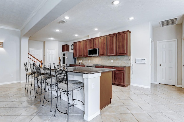 2102 Ivy Cove Ct, Katy, TX 77494 - kitchen with stainless steel microwave, crown molding, a breakfast bar area, light tile patterned floors, and backsplash