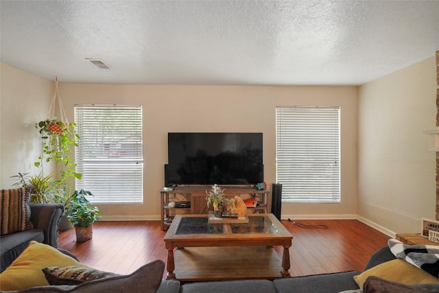33 Coralberry Rd, The Woodlands, TX 77381 - living room with hardwood / wood-style floors, baseboards, a textured ceiling, and a fireplace with raised hearth