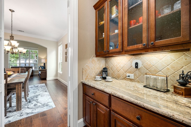6019 Majestic Pines Dr, Houston, TX 77345 - bar with a chandelier, arched walkways, crown molding, decorative backsplash, and pendant lighting