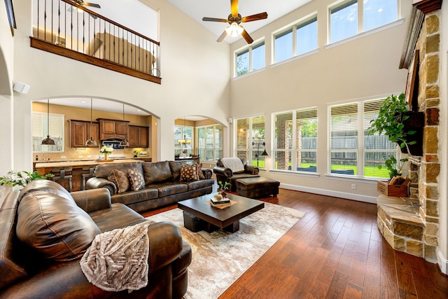 6019 Majestic Pines Dr, Houston, TX 77345 - living room featuring a ceiling fan, dark wood-style flooring, a towering ceiling, arched walkways, and baseboards