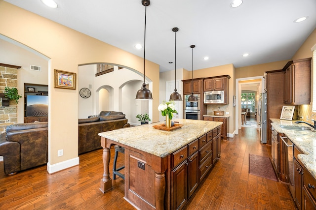 6019 Majestic Pines Dr, Houston, TX 77345 - kitchen with appliances with stainless steel finishes, open floor plan, a sink, light stone countertops, and a center island