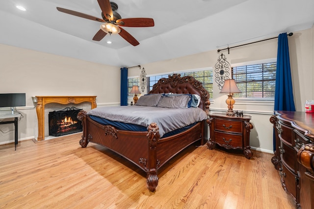 3002 Ashford Oak Dr, Houston, TX 77082 - bedroom featuring light wood-style flooring, ceiling fan, a lit fireplace, lofted ceiling, and baseboards