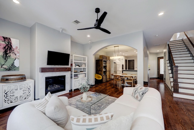 1540 Lawrence St, Houston, TX 77008 - living room with a ceiling fan, dark wood-style floors, a glass covered fireplace, arched walkways, and stairs