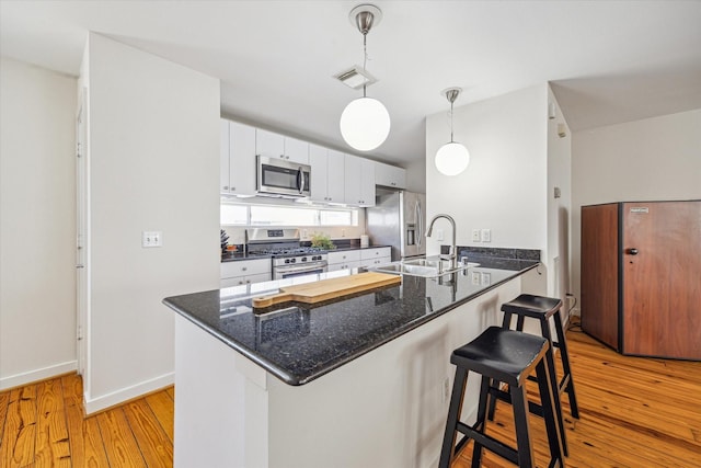 2720 La Branch St, Houston, TX 77004 - kitchen featuring appliances with stainless steel finishes, a peninsula, a sink, a breakfast bar, and light wood finished floors