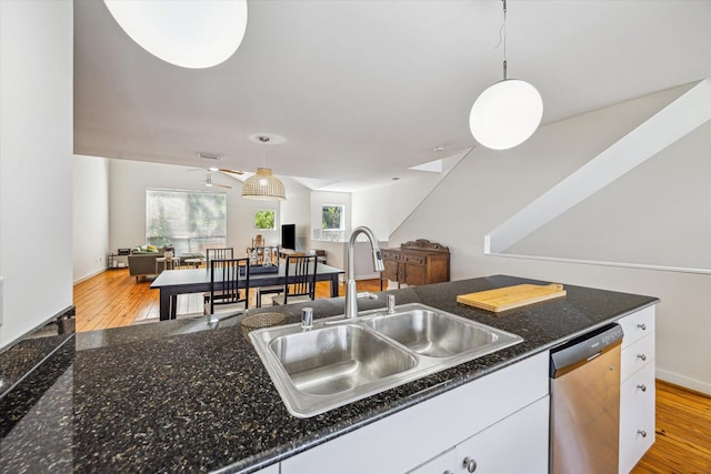 2720 La Branch St, Houston, TX 77004 - kitchen featuring stainless steel dishwasher, a sink, white cabinetry, decorative light fixtures, and light wood-style floors