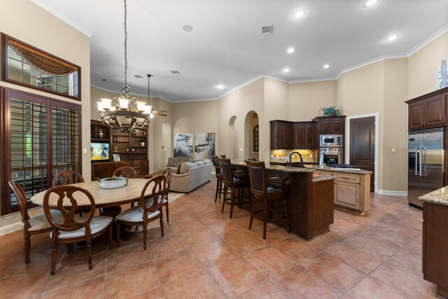 4022 Hidden Winds Dr, Spring, TX 77386 - kitchen featuring built in appliances, arched walkways, a center island with sink, a breakfast bar, and a chandelier