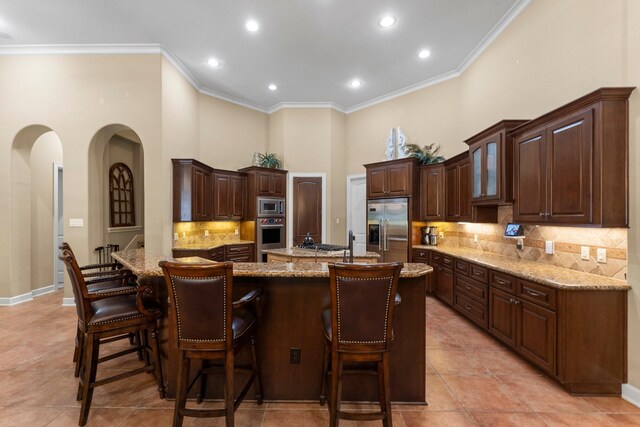 4022 Hidden Winds Dr, Spring, TX 77386 - kitchen with built in appliances, an island with sink, arched walkways, decorative backsplash, and a breakfast bar
