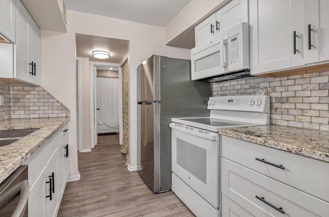 3220 69th St Unit B8, Galveston, TX 77551 - kitchen featuring white appliances, backsplash, light wood-style floors, and white cabinetry